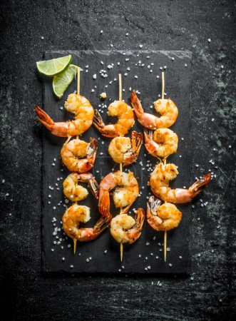 Fragrant shrimps grilled on a stone Board. On dark rustic background