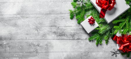 Téléchargez les photos : Coffrets cadeaux sur branches d'arbres de Noël. Sur fond rustique blanc - en image libre de droit