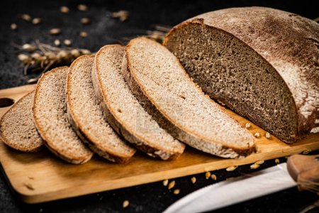 Photo for Sliced rye bread on a cutting board. On a black background. High quality photo - Royalty Free Image