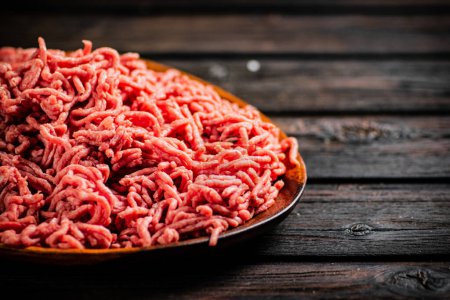 A wooden plate full of minced meat. On a wooden background. High quality photo