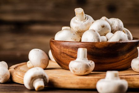 Photo for Mushrooms in a bowl on a cutting board. On a wooden background. High quality photo - Royalty Free Image