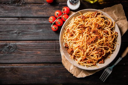 Spaghetti bolognese in a plate on a table with tomatoes. On a wooden background. High quality photo Poster 658487448