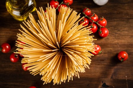 Téléchargez les photos : Spaghettis secs aux tomates cerises. Sur un fond en bois. Photo de haute qualité - en image libre de droit