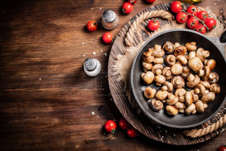 Photo for Frying pan with fried mushrooms on a wooden tray. On a wooden background. High quality photo - Royalty Free Image