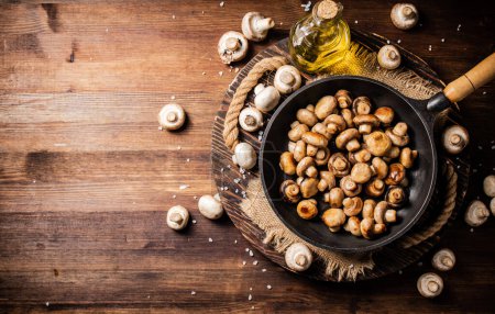 Photo for Frying pan with fried mushrooms on a wooden tray. On a wooden background. High quality photo - Royalty Free Image