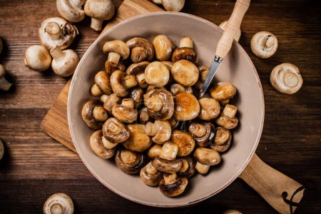 Téléchargez les photos : Fried mushrooms in a bowl on a cutting board. On a wooden background. High quality photo - en image libre de droit