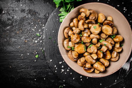 Téléchargez les photos : Delicious fried mushrooms in a bowl. On a black background. High quality photo - en image libre de droit
