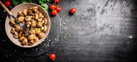 Photo for Fried mushrooms in a bowl with greens and tomatoes on a stone board. On a black background. High quality photo - Royalty Free Image