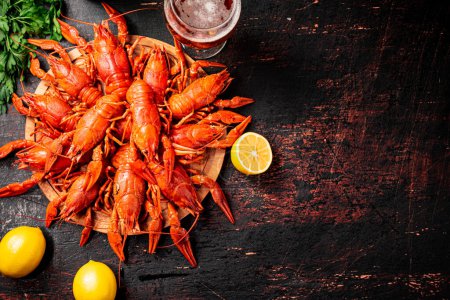 Boiled crayfish with a glass of beer and lemon. Against a dark background. High quality photo