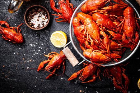 Photo for Boiled crayfish in a colander on a stone board. On a black background. High quality photo - Royalty Free Image