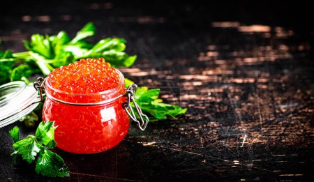 Photo for A full jar of red caviar with parsley on the table. On a rustic dark background. High quality photo - Royalty Free Image