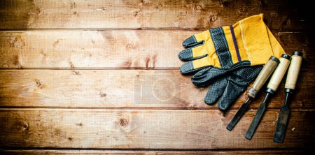 Photo for Chisel with construction gloves on the table. On a wooden background. High quality photo - Royalty Free Image