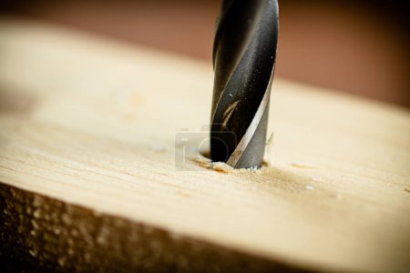 Téléchargez les photos : Piece of wood is drilled with shavings. On a wooden background. High quality photo - en image libre de droit