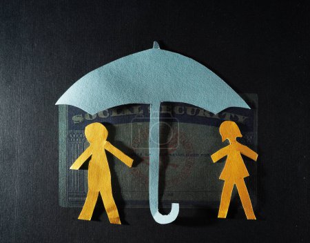 Pareja de papel con tarjeta de Seguro Social y paraguas de papel: seguridad financiera o concepto de ahorro para la jubilación                               