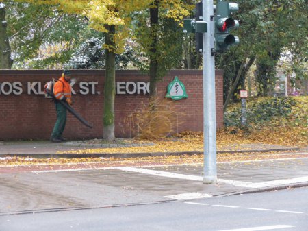 Foto de HAMBURG, ALEMANIA - CIRCA NOVIEMBRE 2016: retirar las hojas del pavimento en otoño - Imagen libre de derechos