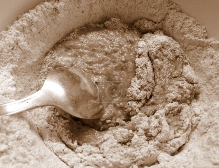 Téléchargez les photos : Adding ingredients for making cocoa flavoured dough, in sepia tones - en image libre de droit