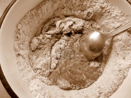 Téléchargez les photos : Adding ingredients for making cocoa flavoured dough, in sepia tones - en image libre de droit