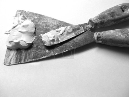 pair of old spatulas loaded with plastic plaster, in black and white