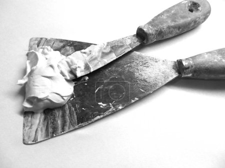 pair of old spatulas loaded with plastic plaster in black and white