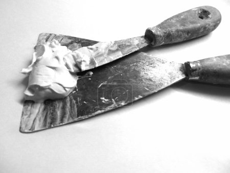 pair of old spatulas loaded with plastic plaster in black and white