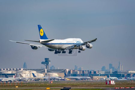 Foto de Frankfurt, Alemania - 20 de marzo de 2024: La Queenoftheskies Boeing 747 de Lufthansa aterriza en el aeropuerto FRA con el horizonte desde Frankfurt en el fondo. - Imagen libre de derechos