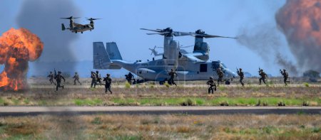 Photo for 2023-09-23: US Marine Corps V-22 Tiltrotor aircraft drop off Marines, who run to the battle. This is a battlefield demonstration at the Miramar airshow. - Royalty Free Image