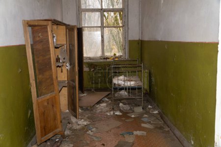 Foto de Muebles de madera destruidos y una cama oxidada para niños dentro de una habitación abandonada en la zona de exclusión de desastres radiactivos del jardín de chernobyl kinder - Imagen libre de derechos