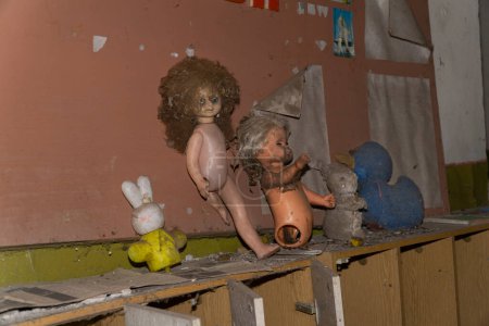 Foto de Viejas muñecas abandonadas y juguetes de animales sobre un mueble de madera dentro de un jardín infantil de chernobyl - Imagen libre de derechos