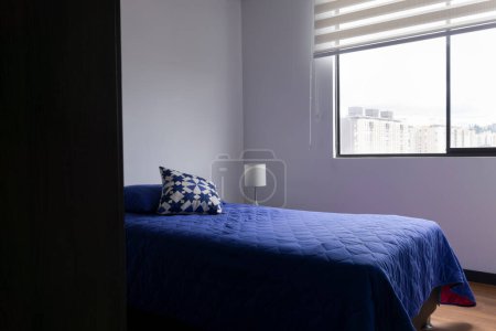 Foto de Hermosa habitación de diseño interior minimalista con una cama individual y un duver azul con diseño geométrico iluminado por la luz natural - Imagen libre de derechos
