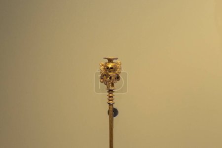 Foto de Forma antropomórfica dorada pequeña en el topp de un palo de madera en el museo de oro - Imagen libre de derechos