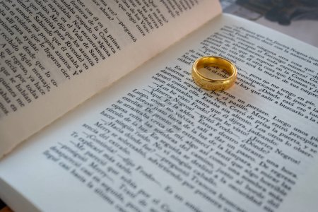 Photo for Closeup to a lord of the rings text book in spanish with the ring of power over the pages - Royalty Free Image