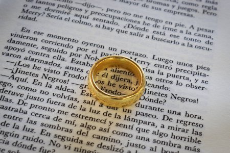 Photo for Closeup to a ring of power of lord of the rings text book in spanish - Royalty Free Image