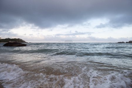 Foto de Hermosa escena de atardecer azul de la playa caribeña colombiana ubicada en el parque tayrona con mar agitado y rocas del océano - Imagen libre de derechos