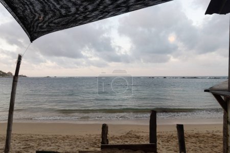 Foto de Hermoso paisaje de mar caribeño al atardecer visto a través de un marco natural en una cabaña roustica en la playa de la piscina en el parque tayrona - Imagen libre de derechos