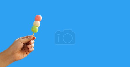 Photo for Japanese dessert, Dango on stick in hand on blue sky - Royalty Free Image
