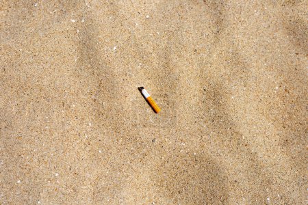Foto de Cigarette butt on sandy beach - Imagen libre de derechos