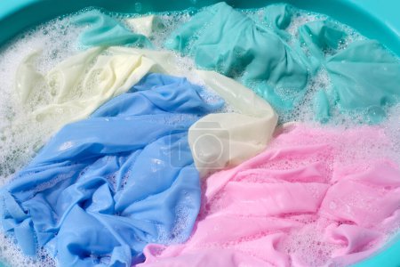 Téléchargez les photos : Vêtements tremper dans la dissolution de l'eau de détergent en poudre, laver les vêtements colorés - en image libre de droit