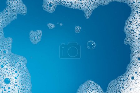 Foto de Burbuja de espuma detergente en el agua. Fondo azul, jabón sud - Imagen libre de derechos