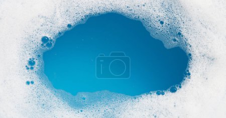 Foto de Burbuja de espuma detergente en el agua. Fondo azul, jabón sud - Imagen libre de derechos