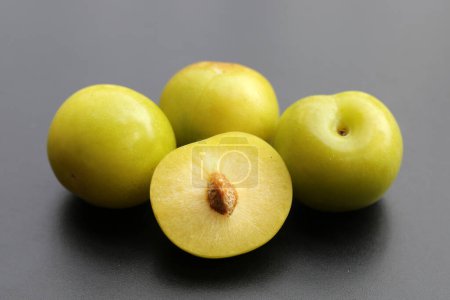 Fruta de ciruela verde fresca sobre fondo oscuro.