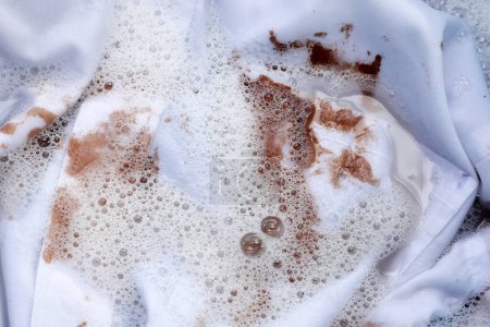 Photo for Dirty choclate stain on white shirt in water with detergent water dissolution, washing cloth - Royalty Free Image