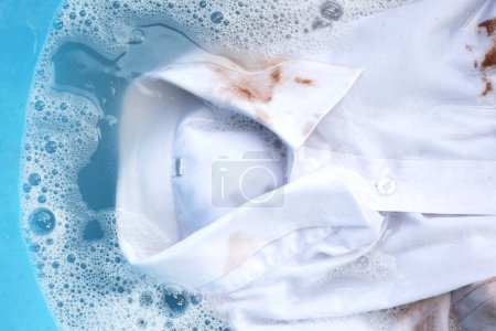 Photo for Dirty choclate stain on white shirt in water with detergent water dissolution, washing cloth - Royalty Free Image