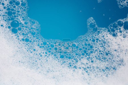 Foto de Burbuja de espuma detergente en Wate. Fondo azul, jabón sud - Imagen libre de derechos