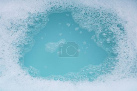 Burbuja de espuma detergente en el agua. Fondo azul, jabón sud