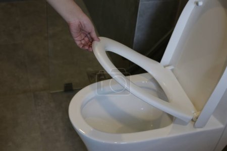 Téléchargez les photos : Main avec couvercle de siège de toilette - en image libre de droit
