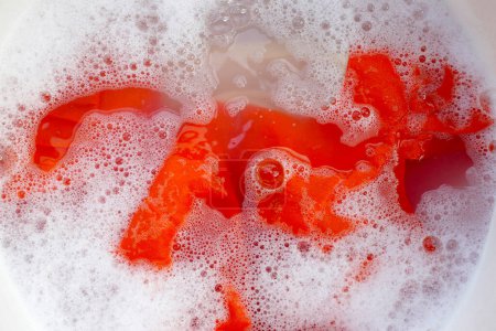 Téléchargez les photos : Robe femme imbibée d'eau détergente dissoute avec bulle de mousse blanche. Concept de blanchisserie - en image libre de droit