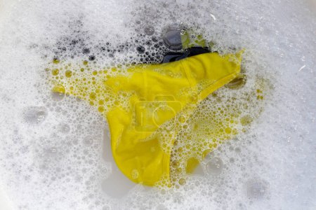 Téléchargez les photos : Sous-vêtements pour hommes trempés dans de l'eau détergent dissous avec bulle de mousse blanche. Concept de blanchisserie - en image libre de droit