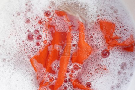 Téléchargez les photos : Robe femme imbibée d'eau détergente dissoute avec bulle de mousse blanche. Concept de blanchisserie - en image libre de droit