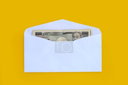 Billete japonés 10000 yenes, dinero japonés en sobre blanco sobre fondo amarillo. Copiar espacio