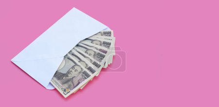 Billete japonés 10000 yenes, dinero japonés en sobre blanco sobre fondo rosa. Copiar espacio